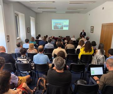 A room full of people sitting in front of a presentation screen